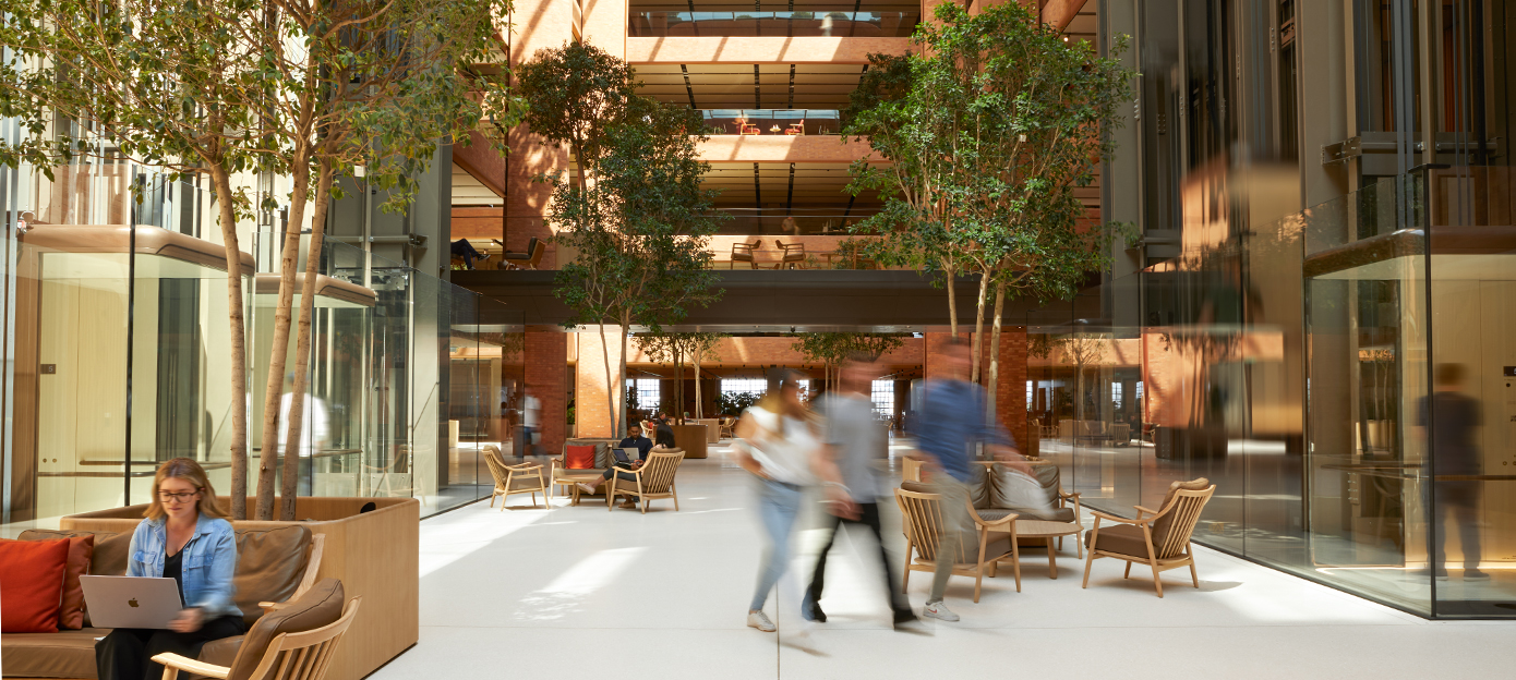 Parter słonecznego atrium Battersea. Widać wielu pracowników Apple, którzy prowadzą rozmowy, dokądś idą lub pracują usadowieni w różnych miejscach.