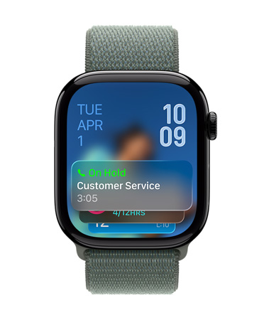 Ada Çayı rengi kayışa sahip Simsiyah Apple Watch'un kadranında altta Tutma Yardımı bildirimi, sol üstte tarih, sağ üstte alt alta dizilmiş saat rakamları görünüyor