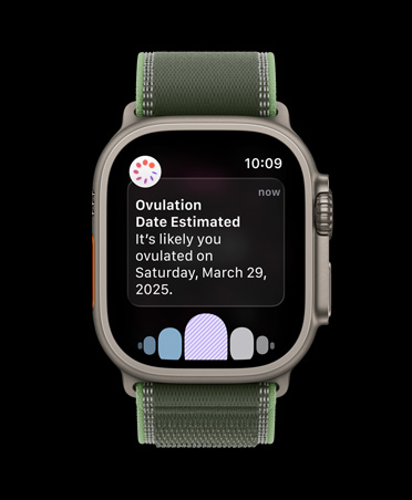 Apple Watch Ultra 3 med urkasse av naturlig titan og Trail Loop i blå/klarblå viser en Syklus-varsling med estimert eggløsningsdato fra Helse-appen.
