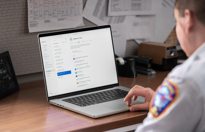 消防署のチームリーダーが、オフィスで座ってMacBookを使用しており、Apple Business Essentialsが表示されている