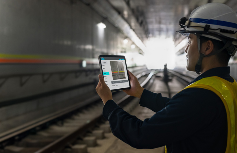 Tokyo Metro 隧道中，和同事協作的一名維護人員正舉起 iPad 拍攝軌道影像。