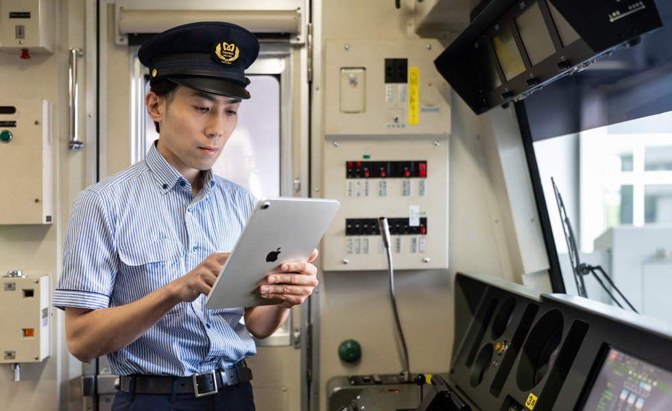明亮的列車駕駛艙內站著一名駕駛員，正與 iPad 進行互動。